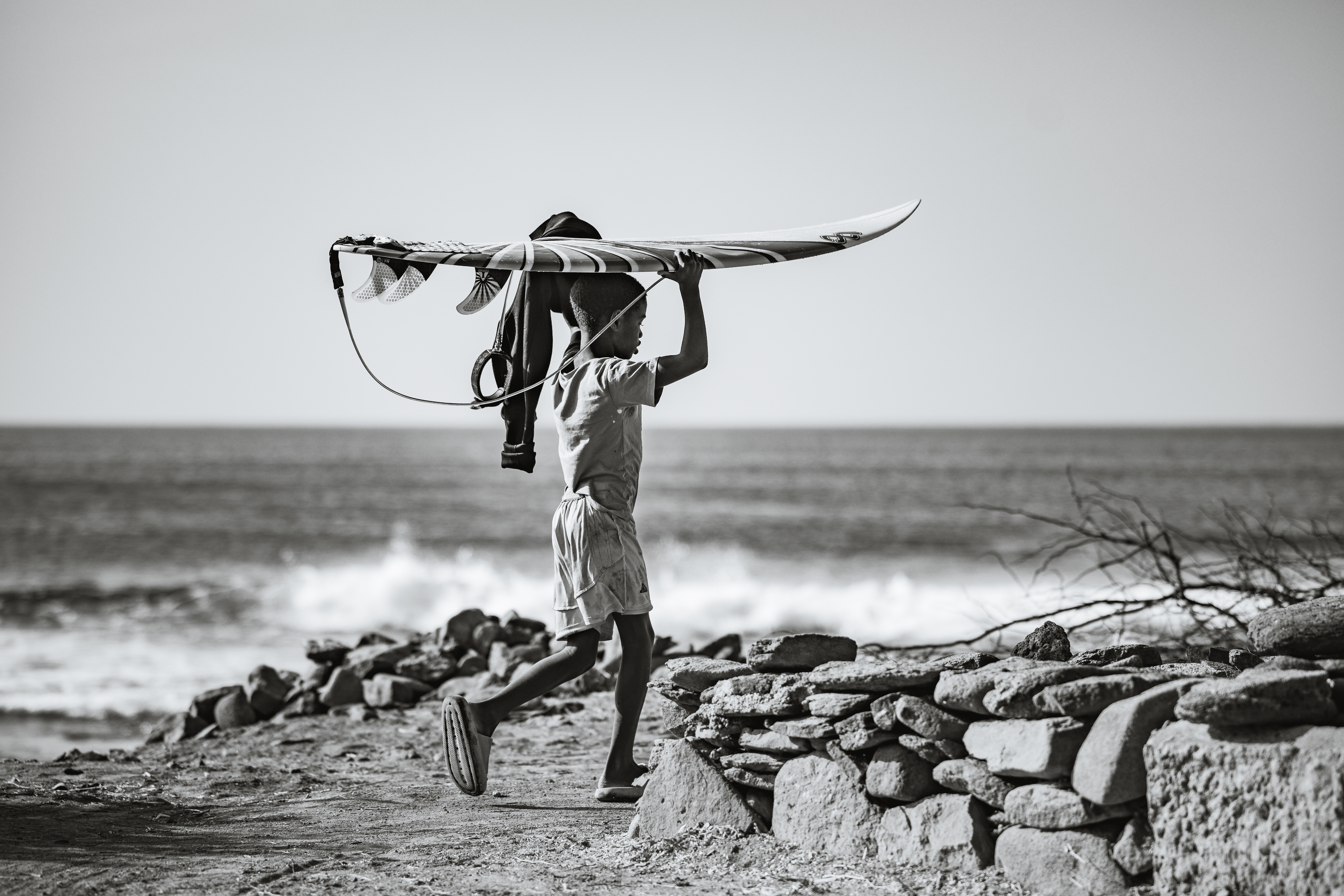 Boy running with surfboard overhead (black & white)