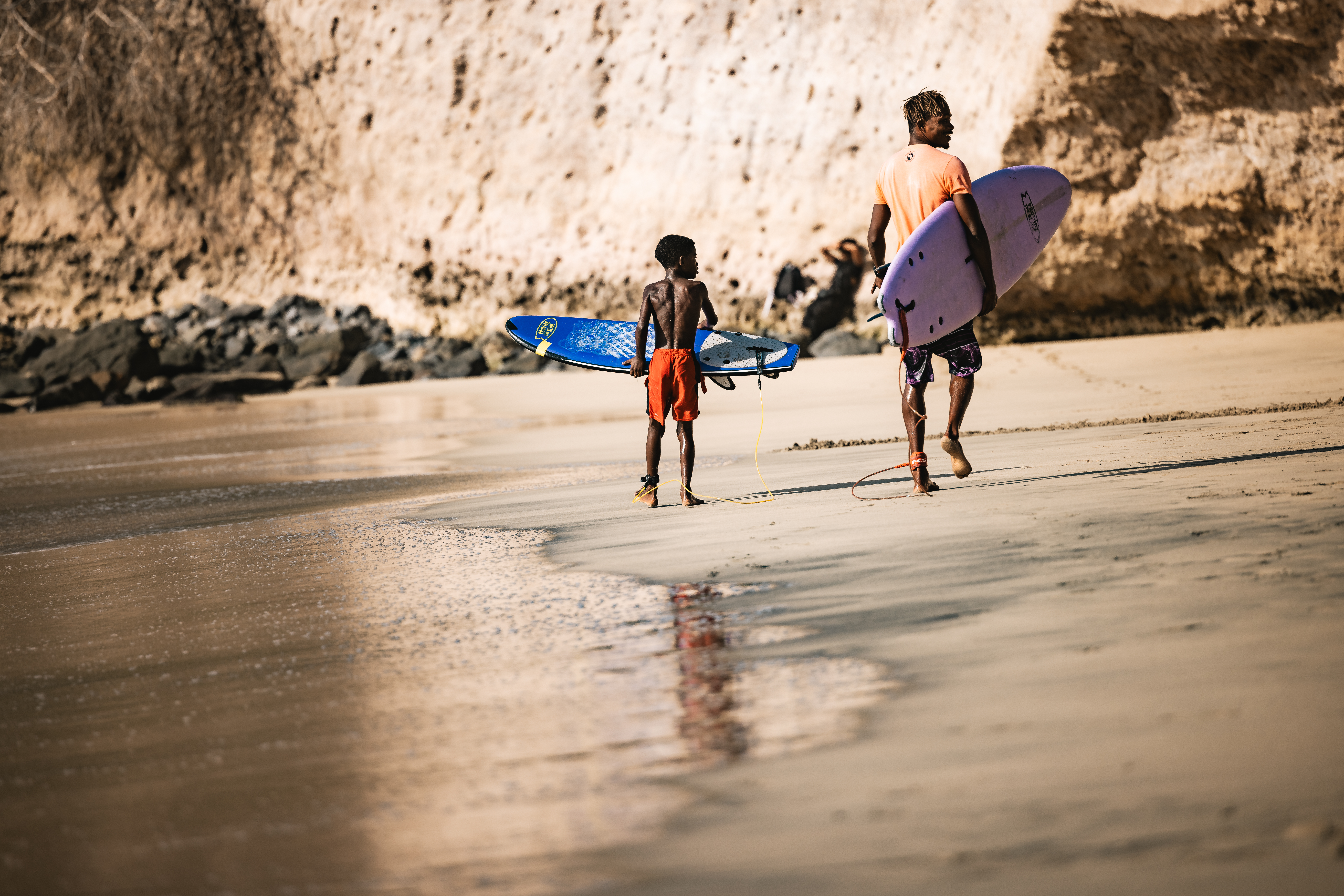 Kabungo and student walking with boards along cliffs