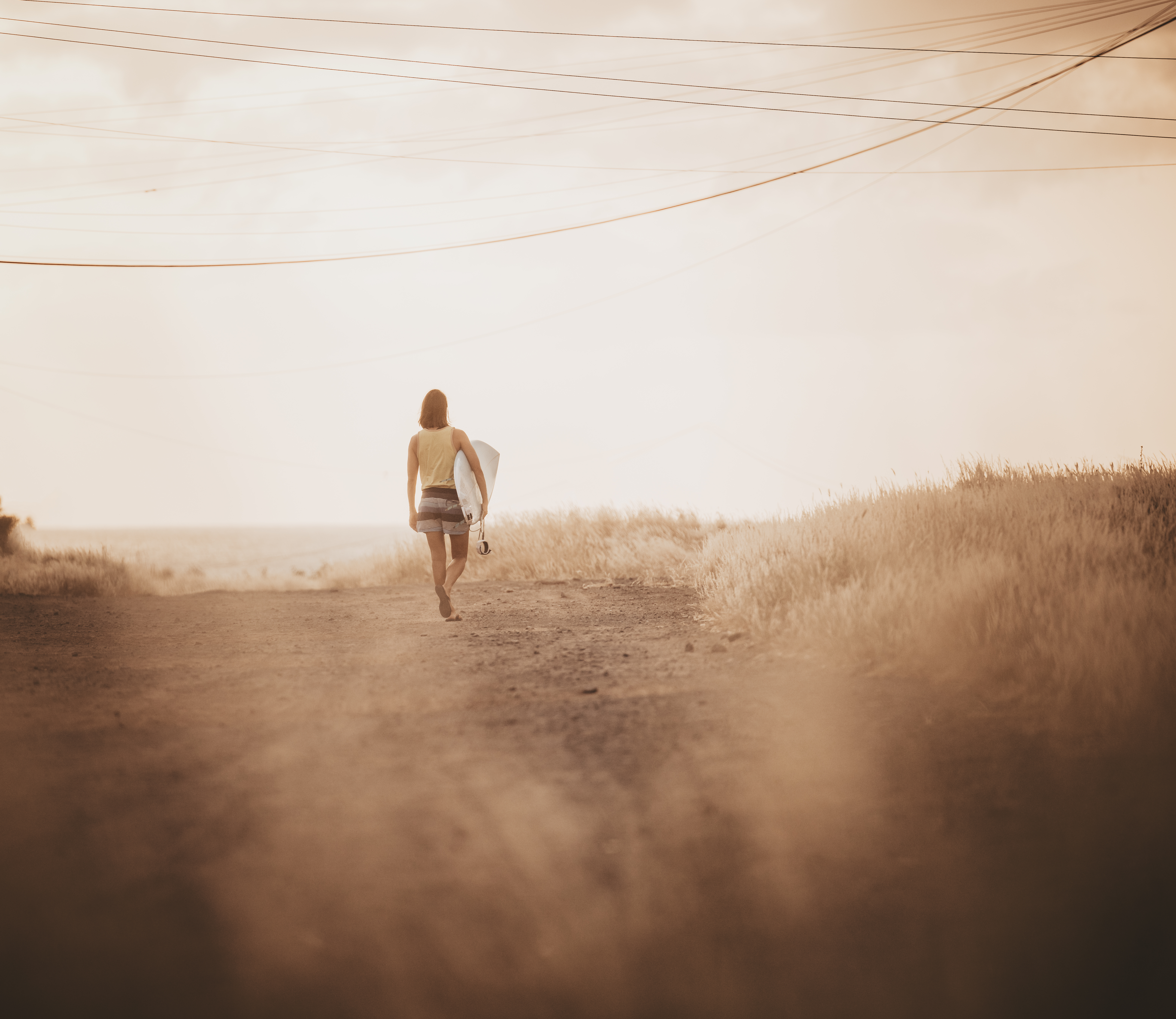 Surfer walking path with power lines